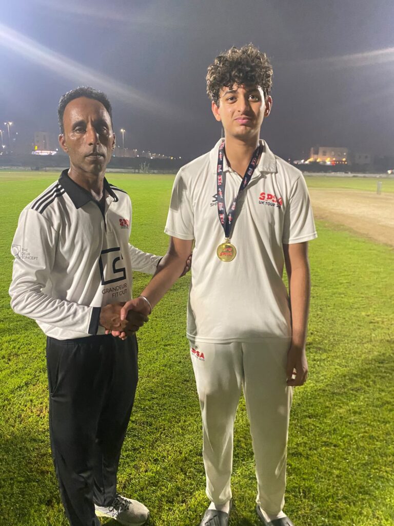 SPSA player receiving the best bowler medal from the umpire under floodlights